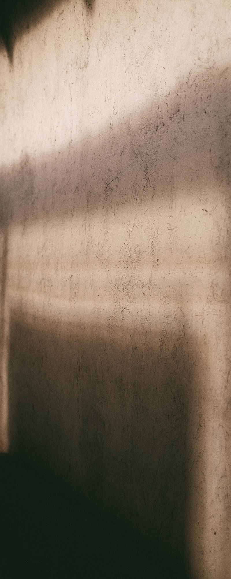 Late-morning light and the shadow of a window frame across a warm plaster wall.